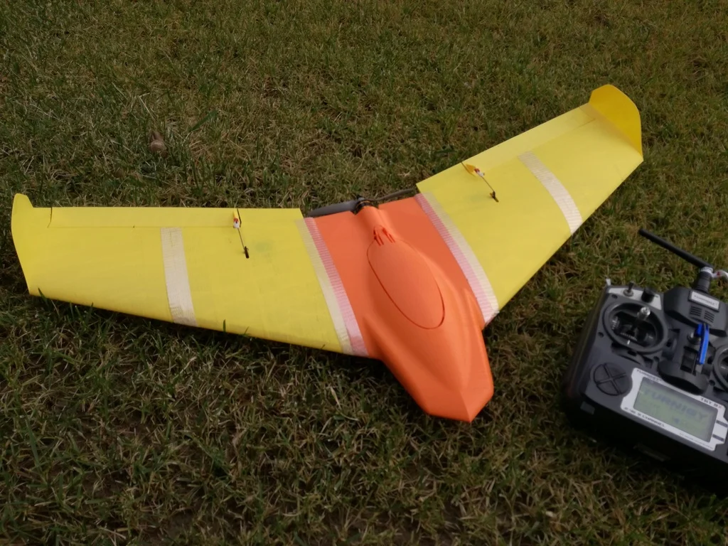 3D printed fixed-wing UAV prototype with radio controller on grass
